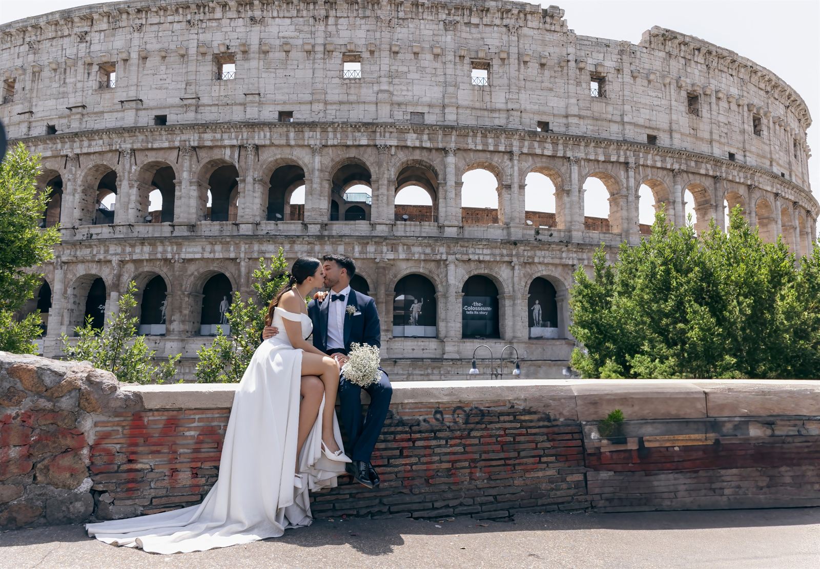 Sposi seduti su un muretto con il Colosseo alle spalle