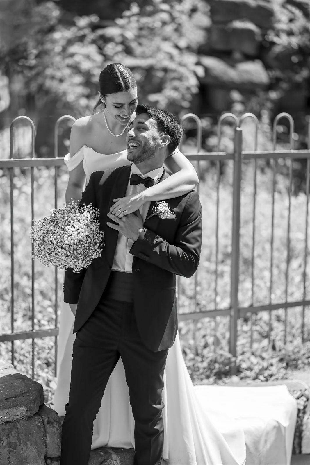 La sposa abbraccia lo sposo da dietro, in bianco e nero