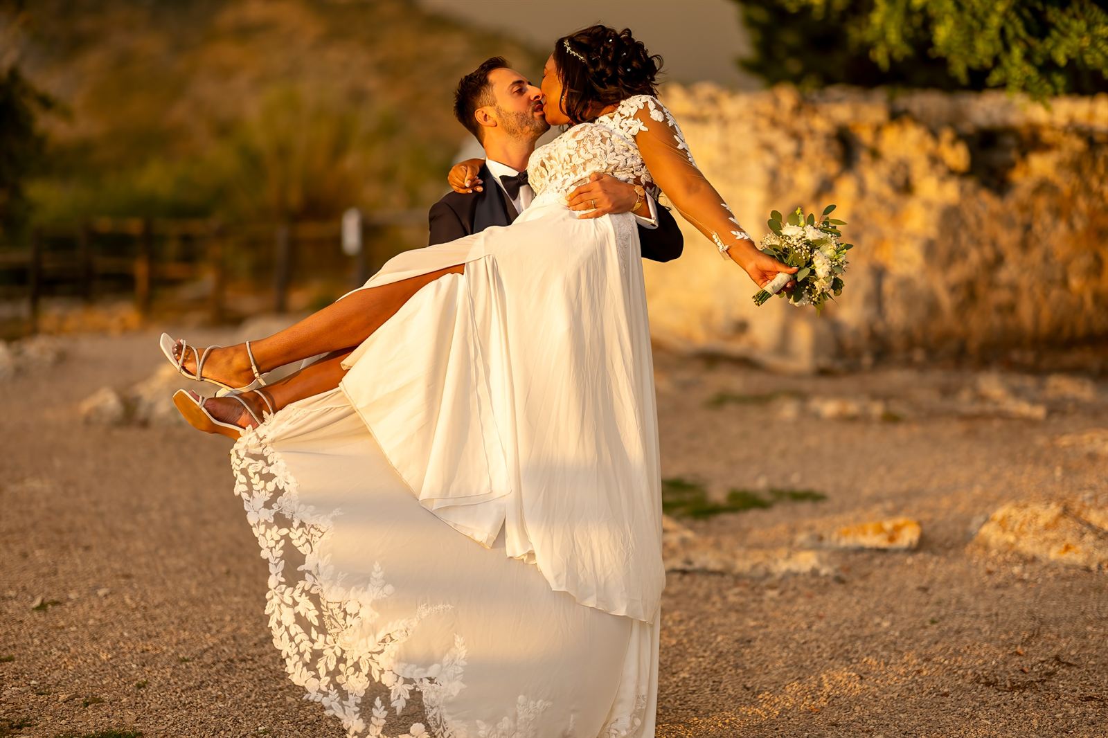 Lo sposo solleva la sposa nella luce calda del tramonto